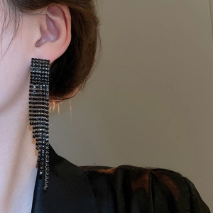 Détail de boucles d'oreilles longues à franges avec strass sombres portées par un mannequin