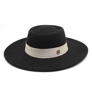 Close-up of black wool fedora featuring a beige ribbon band and golden M letter detail