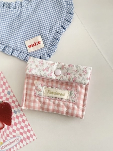 Close-up of a pink checkered floral pouch with a purple button and quilted fabric texture