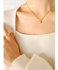 Vue détaillée d'un collier pendentif LUCKY doré et d'une bague large sur un mannequin