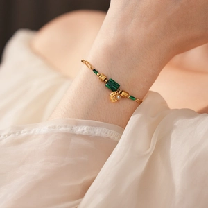 Détail d'un bracelet vintage en chaîne dorée avec perles de malachite et charm micro-pavé