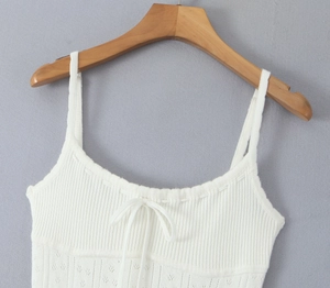 Détail de caraco en tricot blanc avec petit nœud et motifs ajourés élégants