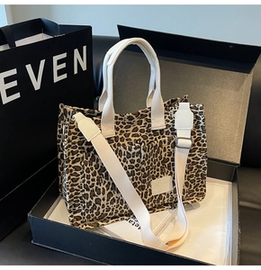Macro detail of leopard print canvas tote bag with white webbing straps and logo patch