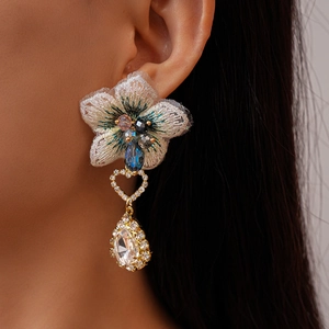 Détail de boucles d'oreilles fleurs en tissu vintage avec cœur strass et gouttes