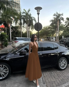 Detail des tiefen V-Ausschnitts und Neckholder-Designs am fließenden braunen Maxikleid