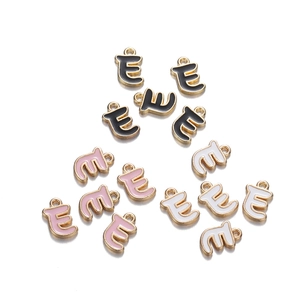 Macro detail of letter E enamel charms in black, pink, and white with golden metal finish