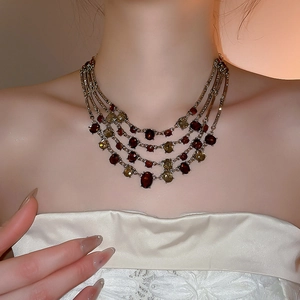 Detail of vintage style multilayered necklace featuring deep red and amber beads