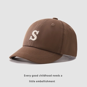 Dettaglio cappello bambino marrone scuro con lettera S ricamata bianca e luce soffusa
