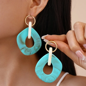 Detail of geometric acrylic earrings with turquoise marble texture worn by a model