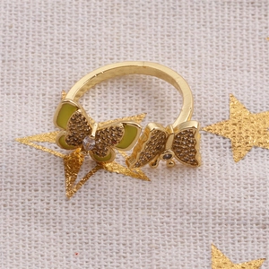Detailed view of gold butterfly ring with green zircon stones and white crystals