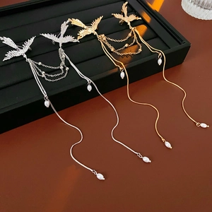 Detail view of bird-shaped brooches with pearl tassels in gold and silver finish