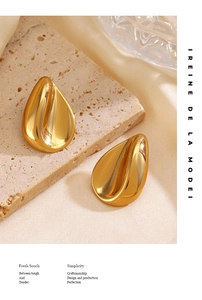 Detail view of twisted gold-plated heart earrings on luxury silk and stone