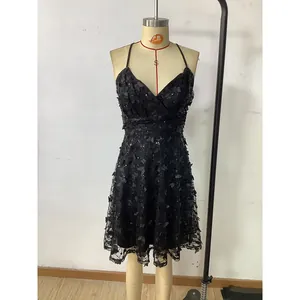 Détail d'une robe courte noire col en V avec des appliques papillons 3D et sequins