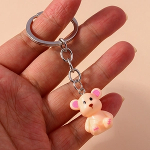 Close-up of a cream bear keychain with pink ear details and silver metal keyring