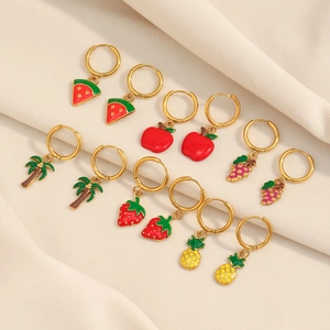 Detail view of gold hoop earrings with enamel fruit charms like watermelon and pineapple