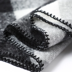 Detail showing the overlock edge stitching on black and white plaid cashmere scarf