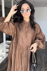Detail of loose brown ramie dress featuring front pleats and button-up mandarin collar