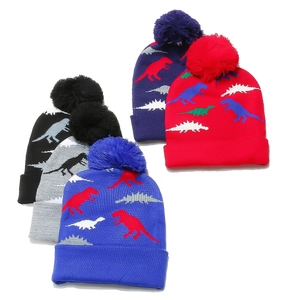Close-up of knit hats with dinosaur jacquard and fluffy pom-poms in five colors