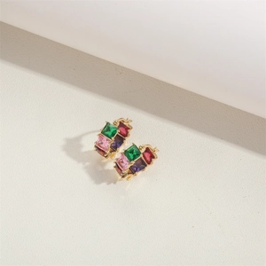 Macro detail of gold earrings with square cut emerald, ruby, and amethyst zircons