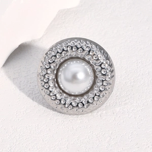 Hammered stainless steel ring with center pearl inlay displayed on a textured stone surface