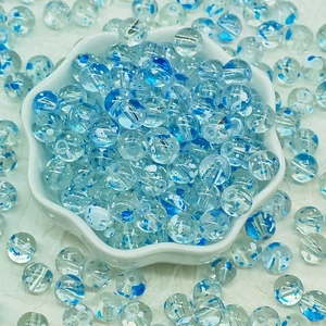 Macro detail of blue floral glass beads in a white ceramic bowl for DIY jewelry