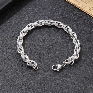 Detail view of silver oval woven chain bracelet with lobster clasp on a dark background