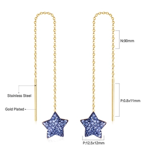 Detail view of gold-plated stainless steel tassel earrings with blue star pendants