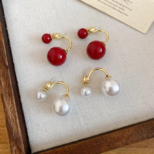 Dettaglio degli orecchini a forma di C placcati oro 14k con perle rosse e crema