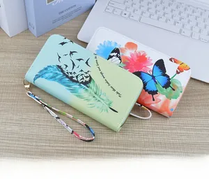 Detail of two floral zip wallets with hand straps on a wooden desk with a laptop