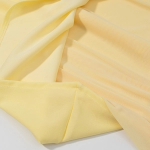 Gros plan sur tissu mousseline jaune pâle montrant coutures fines et texture translucide