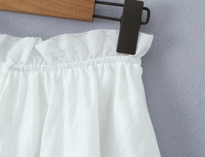 Detail of white lace shorts with elastic ruffled waist and delicate ribbon bow accent