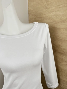 Close-up of white ribbed knit fabric texture on a slim fit long-sleeve top