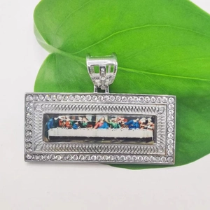 Detailed view of The Last Supper pendant with rhinestone border on a green leaf