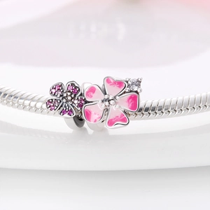 Detalle de pulsera de cadena de serpiente de plata con flor de esmalte rosa y dijes