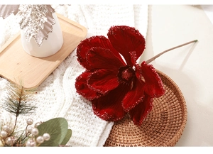 Close-up of a red velvet Christmas flower with glitter edges on a woven tray