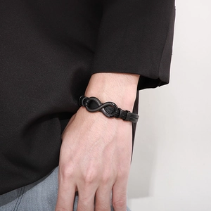 Detail of men's black braided leather bracelet with infinity symbol magnetic clasp