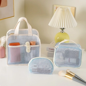 Three-piece set of blue mesh storage bags including tote and pouches on a vanity desk