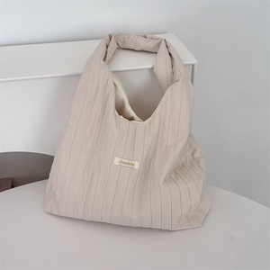 Detail of minimalist pleated cream shoulder bag with Senahha woven label and texture
