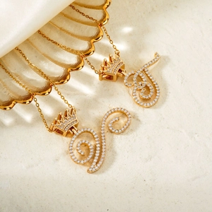 Elegant gold crown initial necklace with cubic zirconia pendants on shell tray