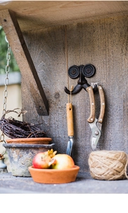 Detail van vintage gietijzeren snor wandhaak voor tuingereedschap op houten wand