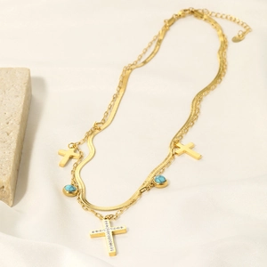 Detail of gold double-layer cross necklace with turquoise beads on white silk