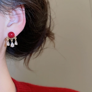 Macro view of vintage pearl drop earrings with red enamel and zircon accents on model