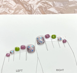 Detail of purple and green press-on toenails with colorful glitter finish on card