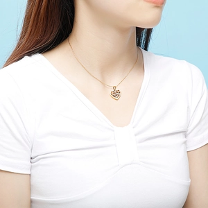 Ensemble bijoux collier coeur évidé doré porté par un mannequin sur fond bleu clair