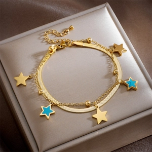 Detailed shot of double-layer gold chain bracelet with star charms on silk cushion