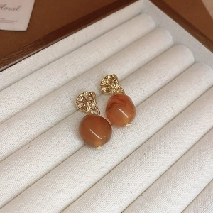 Close-up of vintage gold pleated metal earrings with amber resin beads on jewelry tray