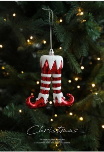 Close-up of red Christmas elf leg ornaments with glitter hanging on a festive tree