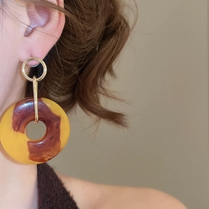 Fashionable resin tortoise shell hoop drop earrings worn by a model in a close-up shot
