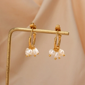 Detail von eleganten Goldohrringen mit mehrschichtigen Süßwasserperlen-Anhängern auf Ständer