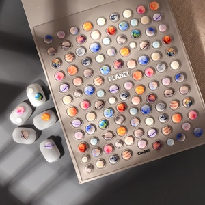 Makroaufnahme von 5D geprägten Planeten-Nagelstickern mit Erde- und Saturn-Motiven auf Nägeln